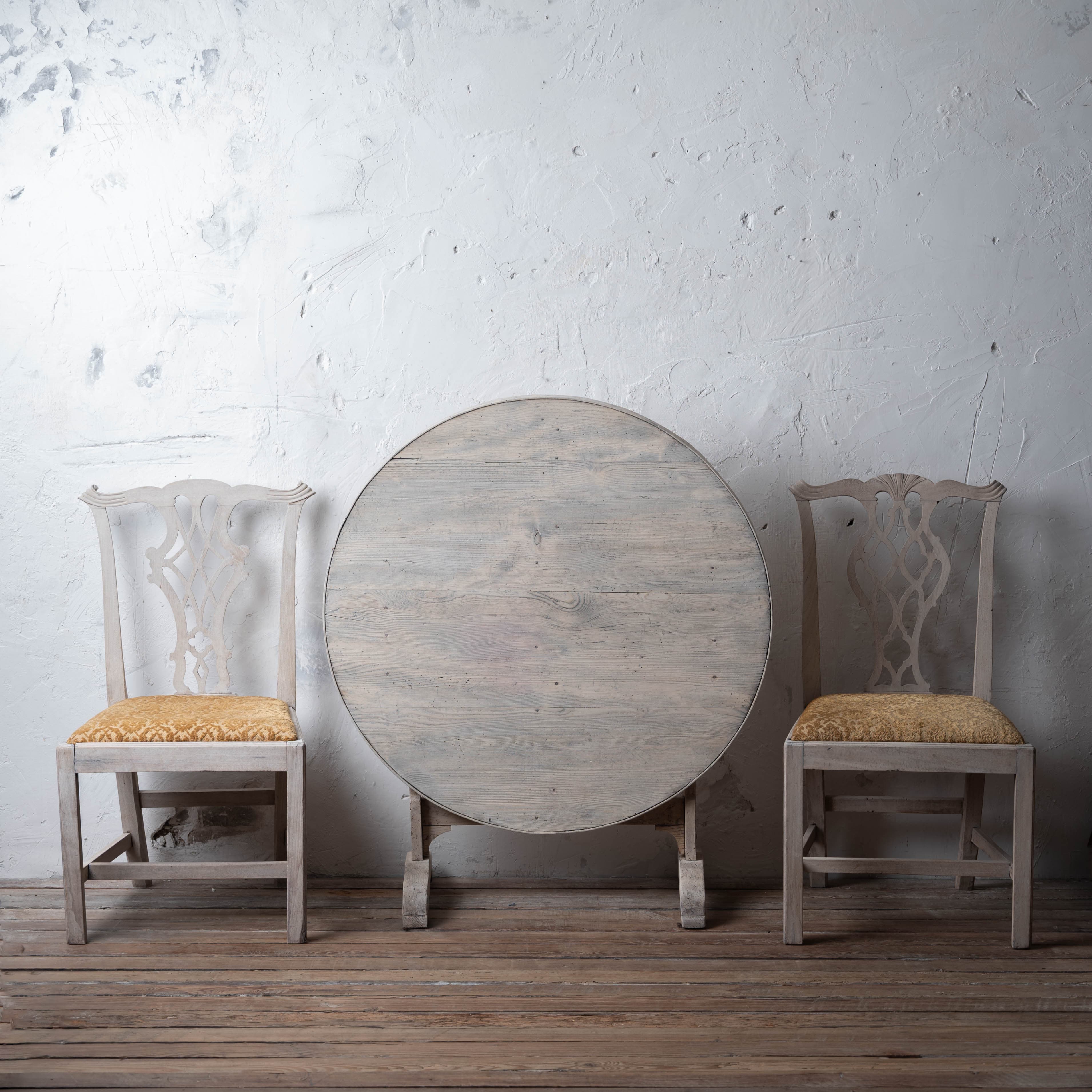 A pair of English Chippendale side chairs flanking a French pine vendange table